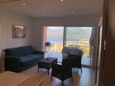 a living room with a couch and chairs and a balcony at punta di buturetu in Propriano