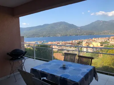 a balcony with a table and a view of the water at punta di buturetu in Propriano