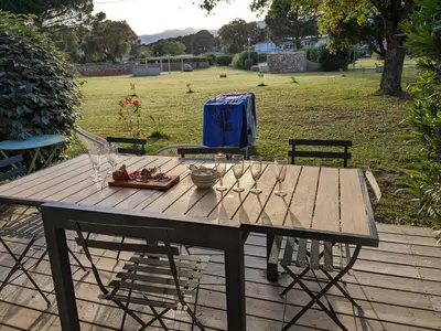 a picnic table with wine glasses and a plate of food at Maison/appartement proche Cala Rossa in Lecci