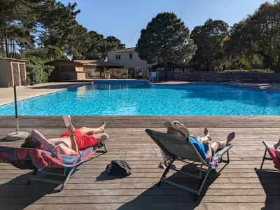 a group of people laying in lawn chairs by a pool at Maison/appartement proche Cala Rossa in Lecci
