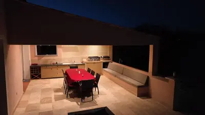 a room with a table and chairs and a kitchen at Villa La Chiappa Bord de Mer avec piscine chauffée et Jacuzzi in Porto-Vecchio