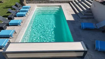 a swimming pool with blue chairs and a green at Villa La Chiappa Bord de Mer avec piscine chauffée et Jacuzzi in Porto-Vecchio