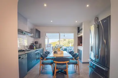 a kitchen with a table and chairs and a refrigerator at Villa La Chiappa Bord de Mer avec piscine chauffée et Jacuzzi in Porto-Vecchio