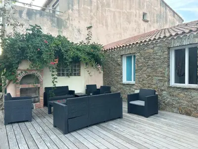 a patio with black furniture on a wooden deck at Maison de charme en bord de mer in Lucciana