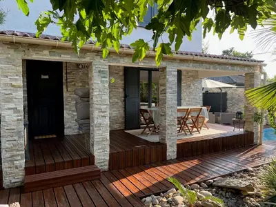 a wooden deck with a dining area on a house at Villa Ponticchio in Santa-Lucia-di-Moriani
