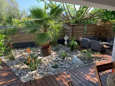 a garden with a deck with a palm tree in it at Villa Ponticchio in Santa-Lucia-di-Moriani
