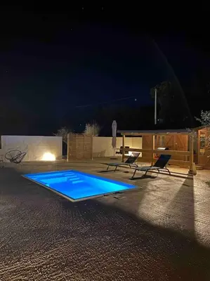 a swimming pool at night with two chairs and a table at Grand chalet d’été avec piscine in Bonifacio