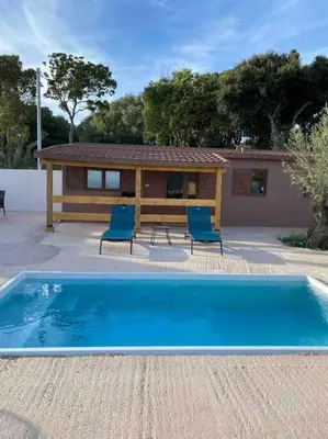 a swimming pool with two chairs and a house at Grand chalet d’été avec piscine in Bonifacio