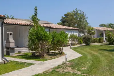 a house with a garden with trees and a sidewalk at A Suara in Ghisonaccia