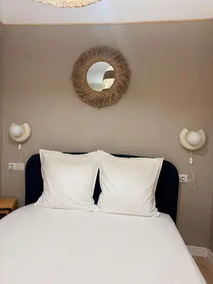 a bed with white pillows and a mirror on the wall at Charmant appartement in Ajaccio