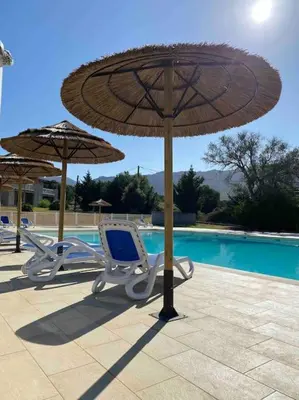 two chairs and an umbrella next to a pool at Saint-Florent Appartement duplex in Oletta