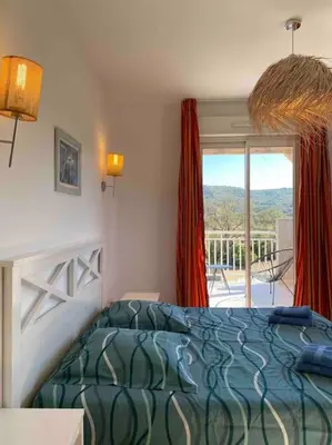 a bedroom with a bed and a view of a balcony at Saint-Florent Appartement duplex in Oletta