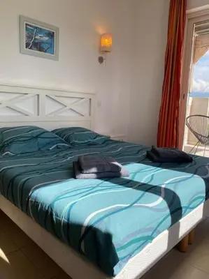 a bedroom with a bed with a blue comforter at Saint-Florent Appartement duplex in Oletta