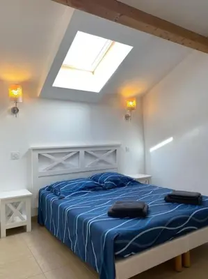 a bedroom with a bed with blue sheets and a skylight at Saint-Florent Appartement duplex in Oletta