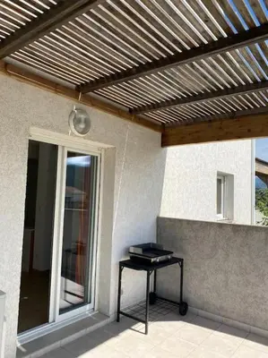 a patio with a wooden pergola and a table at Saint-Florent Appartement duplex in Oletta