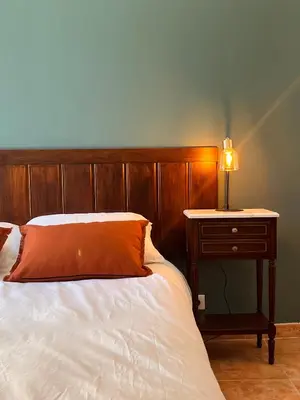 a bed with a wooden headboard and a table with a lamp at Casa Orsini in Nessa