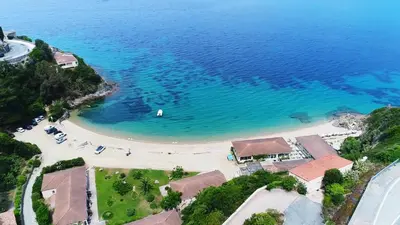 a beach with a view of the water and mountains at Hôtel Sampiero in Propriano