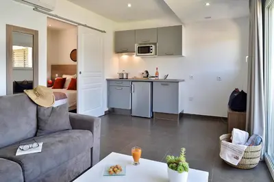 a living room with a couch and a view of the ocean at Hôtel Sampiero in Propriano