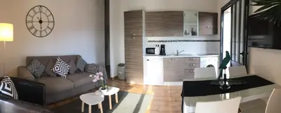 a living room with a couch and a kitchen at Residence Bellavista à Santa Giulia, proche de la plage et vue mer in Porto-Vecchio