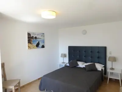 a bedroom with a large bed with a blue headboard at Residence Bellavista à Santa Giulia, proche de la plage et vue mer in Porto-Vecchio