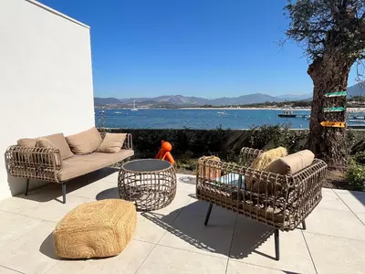 a patio with two chairs and a couch and a table at Le Galatee -T2 luxe les pieds dans l'eau - Porticcio in Porticcio