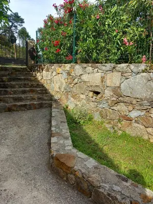 a stone retaining wall with stairs and flowers at A Guinguetta in Venaco