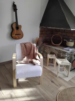 a blanket on a chair in a living room with a guitar at A Guinguetta in Venaco