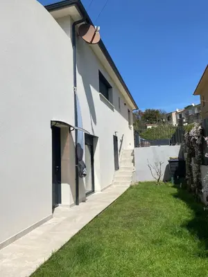 a white building with stairs and a grass yard at Terra bella Costa Verde T2 classé 3 étoiles in San-Nicolao