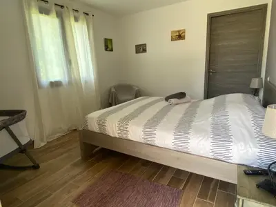 a bedroom with a large bed with a wooden floor at Terra bella Costa Verde T2 classé 3 étoiles in San-Nicolao