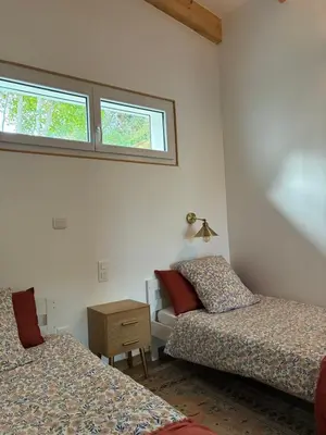 a bedroom with two beds and a table and two windows at Petite maison avec terrasse. in Ajaccio