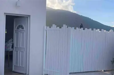a white fence with a white door and a mountain at Petite maison avec terrasse. in Ajaccio