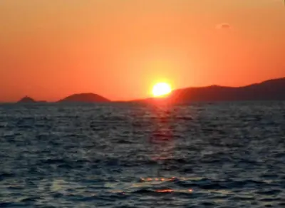 a sunset over the ocean with mountains in the background at Studio 150 m de la plage Agosta in Albitreccia