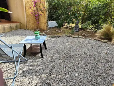 a table and a chair in a gravel yard at Studio 150 m de la plage Agosta in Albitreccia