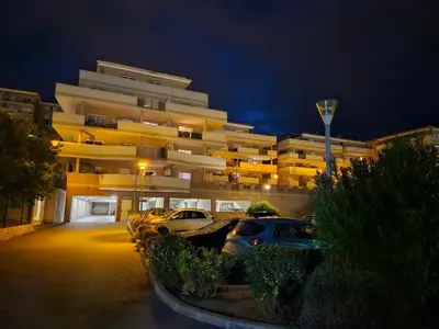 a parking lot in front of a building at night at Appartement cosy climatisé dans résidence fermée in Sarrola-Carcopino