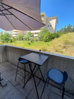 a table and two chairs on a balcony with an umbrella at Appartement cosy climatisé dans résidence fermée in Sarrola-Carcopino