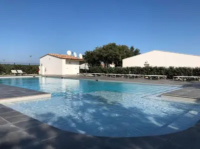 a large swimming pool with blue water in front of a building at Villa Noelly - Résidence les Hauts de Bonifacio in Bonifacio