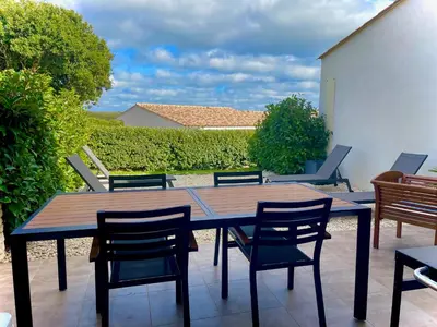 a wooden table and chairs on a patio at Villa Noelly - Résidence les Hauts de Bonifacio in Bonifacio