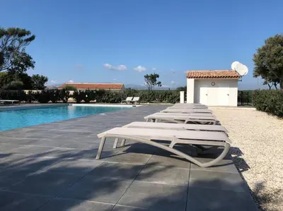 a row of lounge chairs next to a swimming pool at Villa Noelly - Résidence les Hauts de Bonifacio in Bonifacio