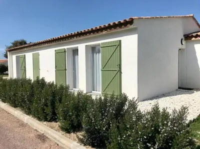 a white building with green doors and some bushes at Villa Noelly - Résidence les Hauts de Bonifacio in Bonifacio