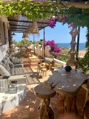 a patio with a table and a view of the ocean at Villa LILY BAY baie de Santa Giulia-Porto Vecchio in Porto-Vecchio