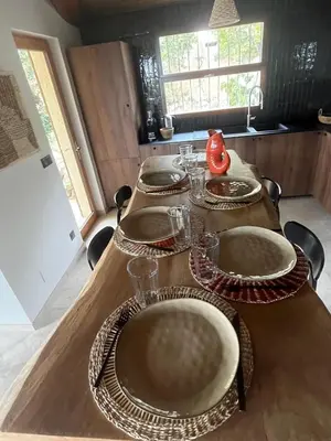 a wooden table with plates and glasses on it at Villa LILY BAY baie de Santa Giulia-Porto Vecchio in Porto-Vecchio