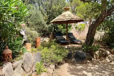 a patio with two chairs and an umbrella at Villa LILY BAY baie de Santa Giulia-Porto Vecchio in Porto-Vecchio