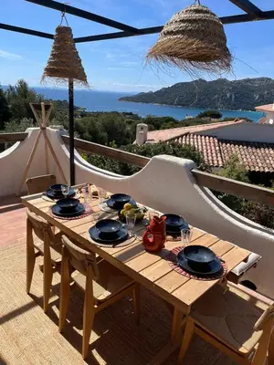 a wooden table with plates of food on top of a balcony at Villa LILY BAY baie de Santa Giulia-Porto Vecchio in Porto-Vecchio