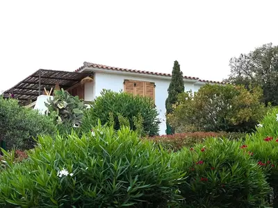a white house with a garden of flowers at Villa LILY BAY baie de Santa Giulia-Porto Vecchio in Porto-Vecchio