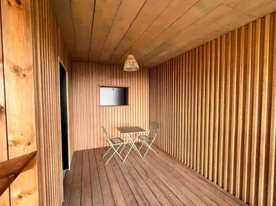 a room with a table and chairs on a wooden deck at Ivona Vacances - Villa de luxe avec piscine chauffée à Santa-Giulia in Porto-Vecchio