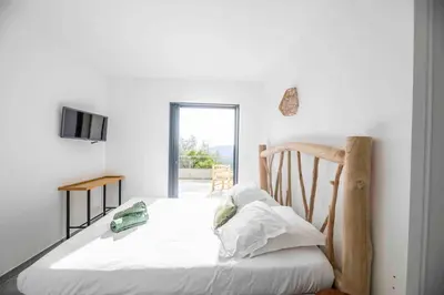 a white bedroom with a bed and a television at Ivona Vacances - Villa de luxe avec piscine chauffée à Santa-Giulia in Porto-Vecchio
