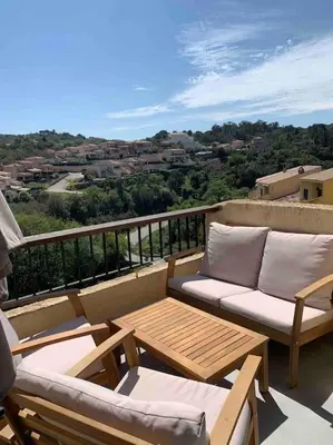 a balcony with two chairs and a table on a balcony at Appartement duplex Porticcio avec parking in Porticcio