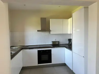 a kitchen with white cabinets and a black appliance at Appartement avec piscine à 50 m de la plage in Propriano