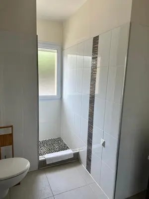 a bathroom with a shower with a toilet and a window at Appartement avec piscine à 50 m de la plage in Propriano