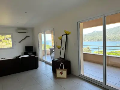 a living room with a couch and a large window at Appartement avec piscine à 50 m de la plage in Propriano